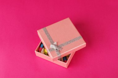 Hediye kutusu ile hapları pembe bir backgroung. Tıp mevcut kavramı