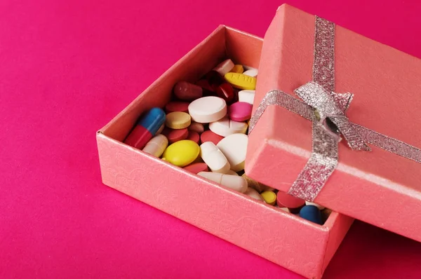 Caja de regalo con pastillas en un fondo rosa. Medicina concepto actual —  Fotos de Stock