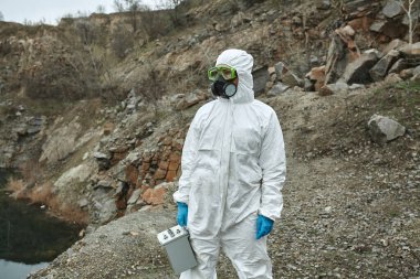 Koruyucu tulumlu bir kız. Biyolojik koruma giysisi, yüzünde maske ve gözlük. Virüsün bulaşmasını önlemek için kişisel koruyucu ekipman. Koronavirüs, salgın, grip ve karantina kavramı.