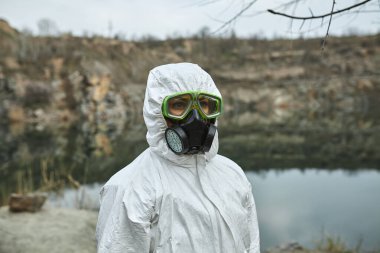 Koruyucu tulumlu bir kız. Biyolojik koruma giysisi, yüzünde maske ve gözlük. Virüsün bulaşmasını önlemek için kişisel koruyucu ekipman. Koronavirüs, salgın, grip ve karantina kavramı.