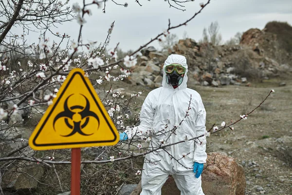 Girl in protective overalls on the nature. Biological protection suit, mask and glasses on the face. Personal protective equipment to prevent transmission of the virus. The concept of coronavirus, pandemic, flu and quarantine. Symbol of biohazard.