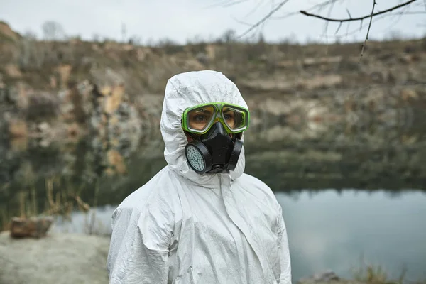 Girl in protective overalls on the nature. Biological protection suit, mask and glasses on the face. Personal protective equipment to prevent transmission of the virus. The concept of coronavirus, pandemic, flu and quarantine.