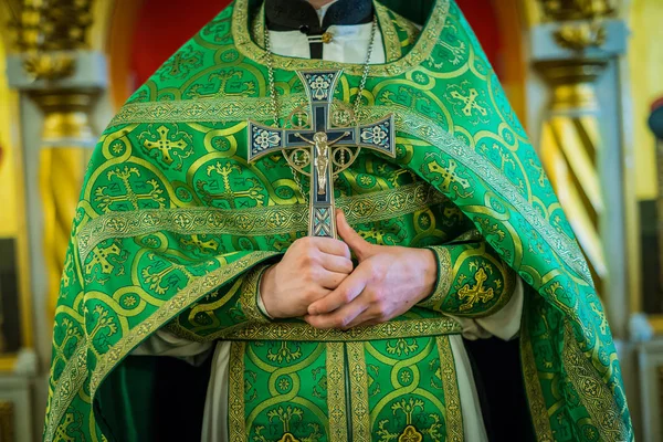 En präst i gröna skrud rymmer ett stort kors på bröstet — Stockfoto