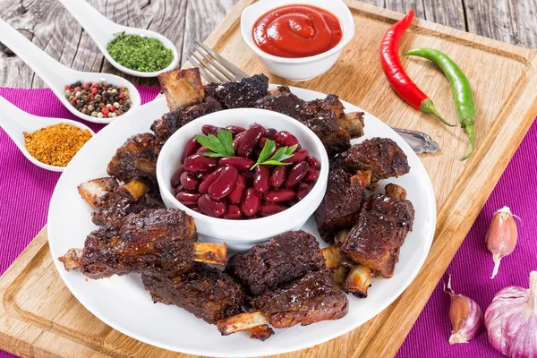 Red beans in bowl surrounded by grilled ribs — Stock Photo, Image