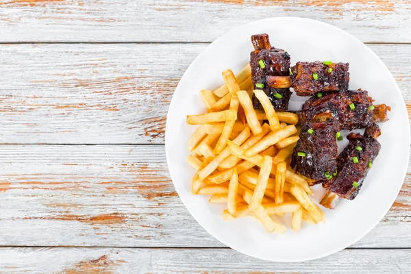 Papas fritas con costillas pegajosas fritas salpicadas con cebolla verde — Foto de Stock