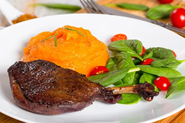 Grilled duck legs marinated in red wine with pumpkin puree — Stock Image Grilled duck legs marinated in red wine with pumpkin puree Royalty Free Stock Images