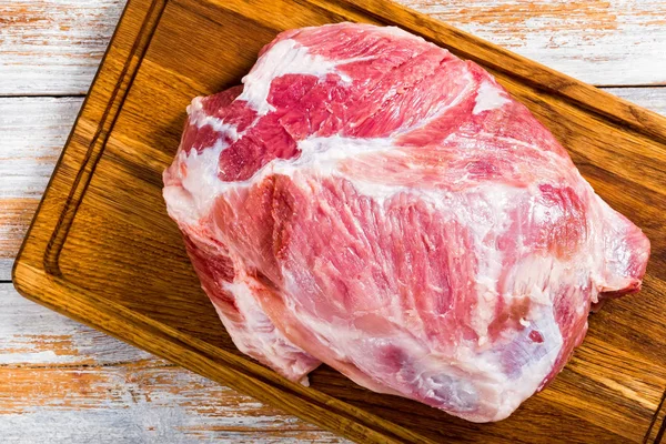 Hombro de cerdo crudo fresco en tabla de cortar de madera —  Fotos de Stock
