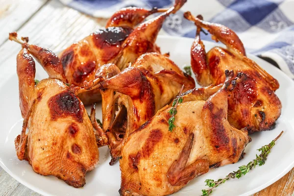 Roasted quails with thyme on dish on white table — Stock Photo, Image