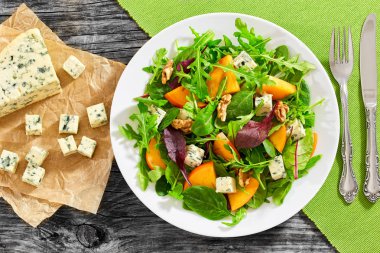 salad with persimmon slices, mix of lettuce leaves, blue cheese  clipart