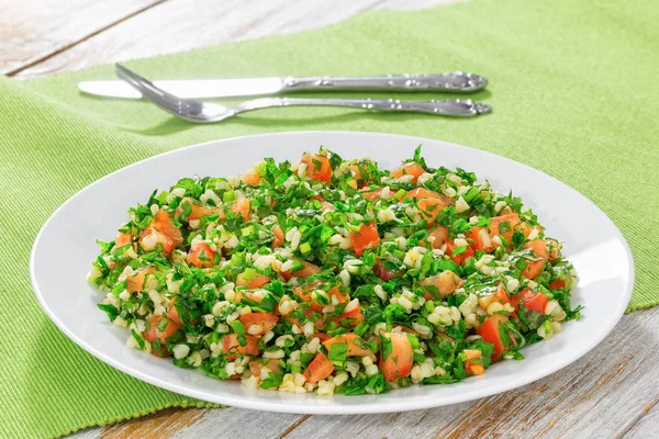 Salade de persil Tabbouleh sur plateau blanc sur tapis de table — Photo