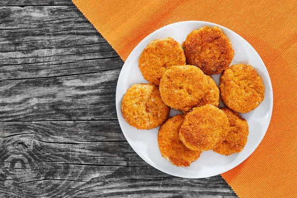 Jugosas y deliciosas chuletas de carne empanada en un plato blanco en viejas tablas de madera oscura, vista desde arriba —  Fotos de Stock