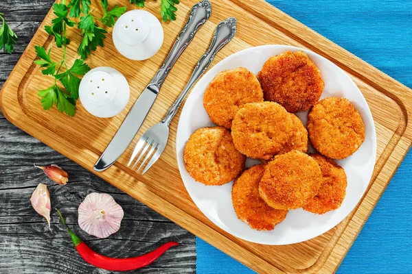 Chicken cutlets on white dish on wooden chopping board — Stock Photo, Image