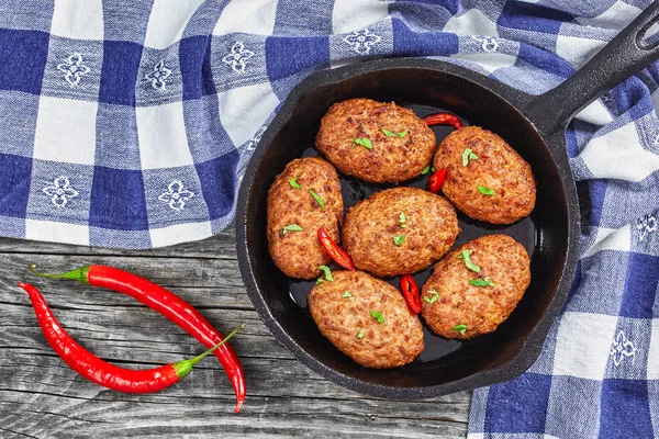 Meat cutlets in iron frying pan sprinkled with chili pieces — Stock Photo, Image