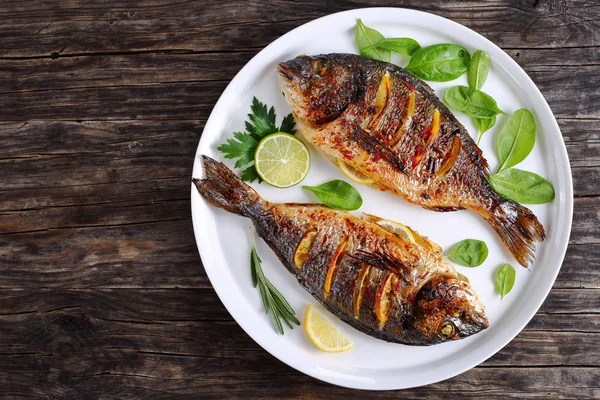 Peixe dourado assado com fatias de limão — Fotografia de Stock