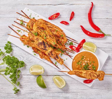Chicken satay on skewers with sauce clipart