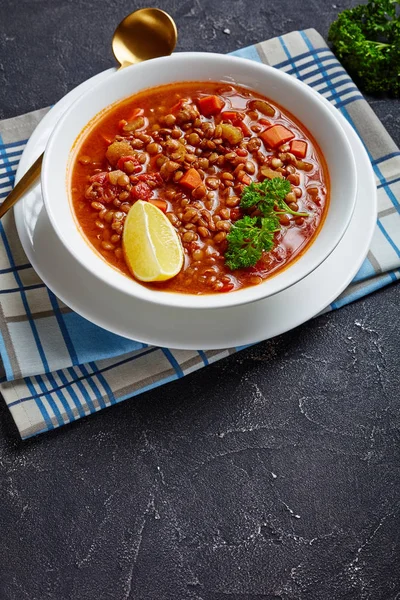 lentil soup with vegetables and a lemon wedge