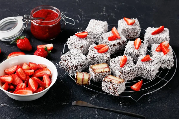 澳大利亚著名的甜点有 用草莓果酱填饱肚子 涂满巧克力和切碎的椰子 放在黑色混凝土背景的圆形铁丝架上 特写特写 — 图库照片