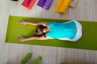 Yoga sınıfında çocuk pozu veren bir kadın. Eline odaklan. en üstteki görünüm