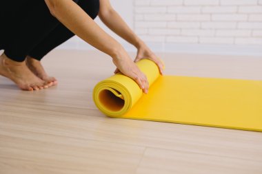 Yoga dersinden sonra paspası yuvarlanan kadın.
