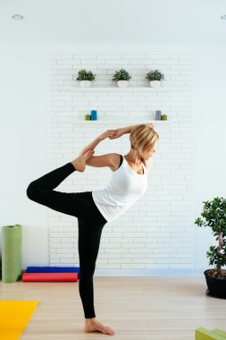 Çekici bir genç kadın bir yoga poz dengesi için yapıyor ve germe