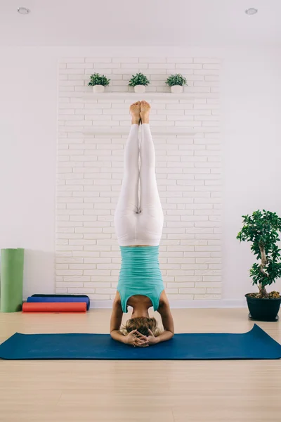 Çekici bir genç kadın bir yoga yaparken Baş stand denge ve germe için poz. Sağlıklı kavramı. — Stok fotoğraf