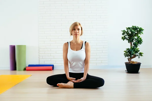 woman doing yoga in studio lotus position with eyes closed
