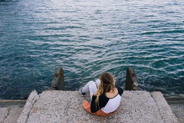 İskelede rahatlatıcı ve denize dört gözle genç kadın