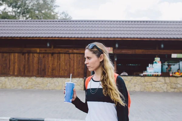 Młoda kobieta spaceru na ulicy i trzymając kubek napój — Zdjęcie stockowe