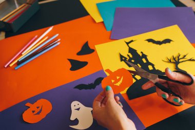 eller arka plan Cadılar Bayramı kompozisyon kağıt kabak kesme makası ile kapatın. Castle, hayaletler, pumpkins, yarasalar ve diğer el yapımı ürkütücü süslemeleri. Cadılar Bayramı tatil kavramı. 