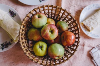 pide ekmeğiyanında pembe bir masa örtüsü üzerinde duran hasır plaka olgun elma