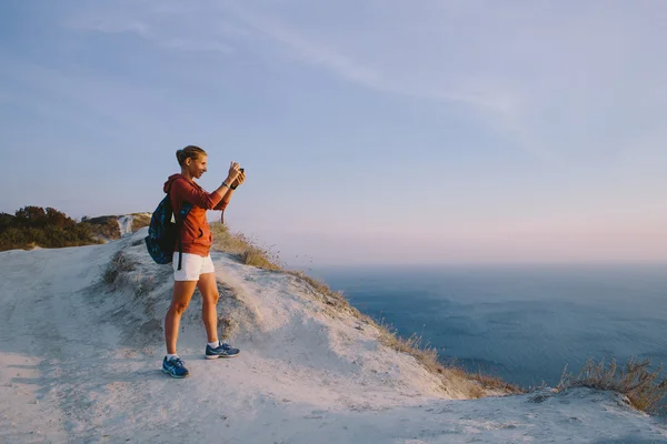 Attraente giovane donna bionda turista prende la foto sulla macchina fotografica retrò sulla cima della montagna sullo sfondo del mare — Foto Stock