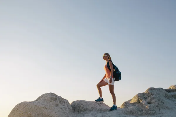 Młoda kobieta turystka z plecakiem stojąca na klifie i patrząca w przyszłość. pani turysta na szczycie góry ciesząc się widokiem przed zachodem słońca — Zdjęcie stockowe