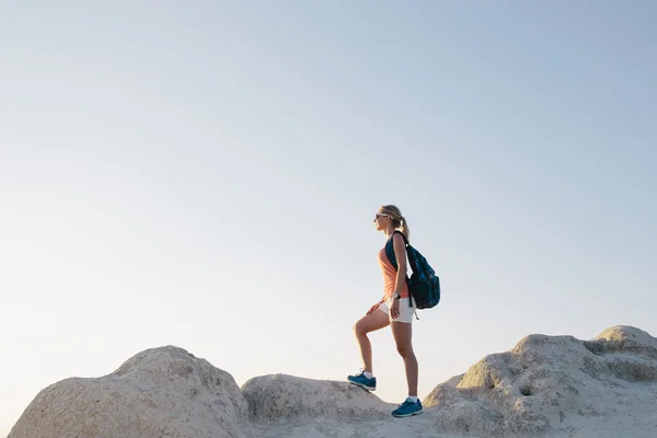 Młoda kobieta turystka z plecakiem stojąca na klifie i patrząca w przyszłość. pani turysta na szczycie góry ciesząc się widokiem przed zachodem słońca — Zdjęcie stockowe