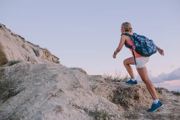 Jovem turista com mochila subindo na montanha — Fotografia de Stock