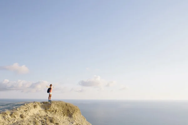 Młoda kobieta turystka z plecakiem stojąca na szczycie góry z podniesionymi rękami. koncepcja wolności — Zdjęcie stockowe