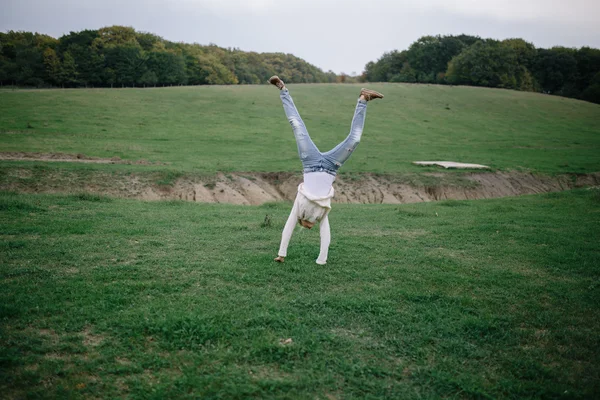 Jovem feliz em uma camisola branca e jeans azul tem ventilador ao ar livre — Fotografia de Stock