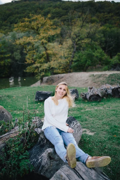 Heureuse jeune femme dans un pull blanc et un jean bleu relaxant à l'extérieur — Photo
