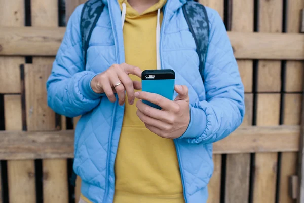 Hombre usando el teléfono inteligente sobre fondo de madera. imagen recortada de un joven enviando un mensaje de texto desde su teléfono celular — Foto de Stock