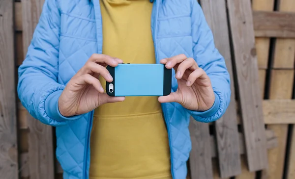 Young man using smart phone. young man in blue jacket uses mobile phone to take photo. — Stockfoto