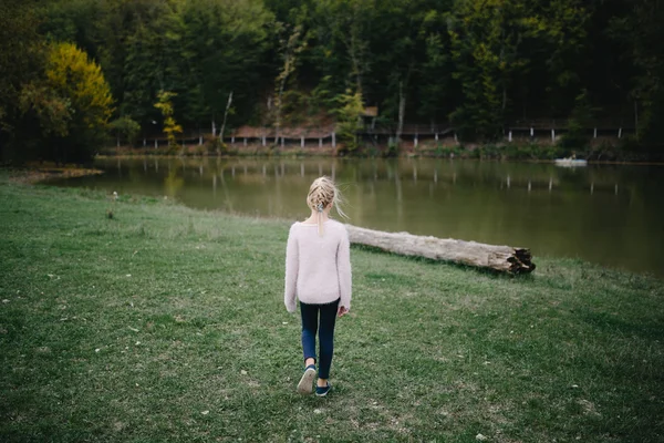 Грустная маленькая девочка идет одна на берегу озера — стоковое фото