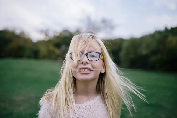 Porträtt av leende rufsig blondin tjej med glasögon utomhus i parken — Stockfoto