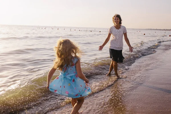 Mulher brinca com sua filha na praia — Fotografia de Stock