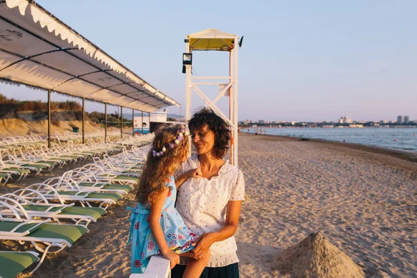 Mãe e filha sentadas na praia . — Fotografia de Stock