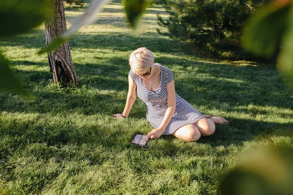 Mujer en el parque sentada en la hierba — Foto de Stock