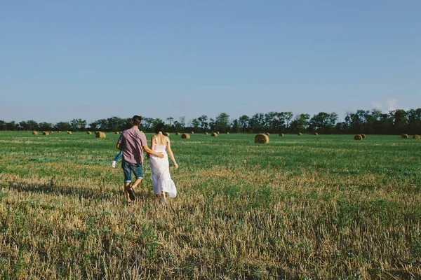 Family with child walking on the field. — Stock Photo, Image