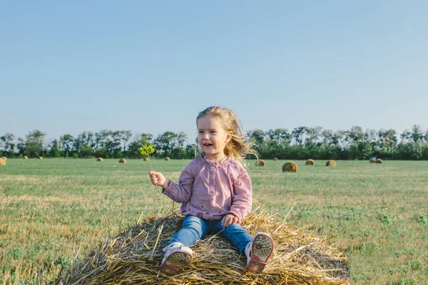 Liten flicka på en höstack — Stockfoto