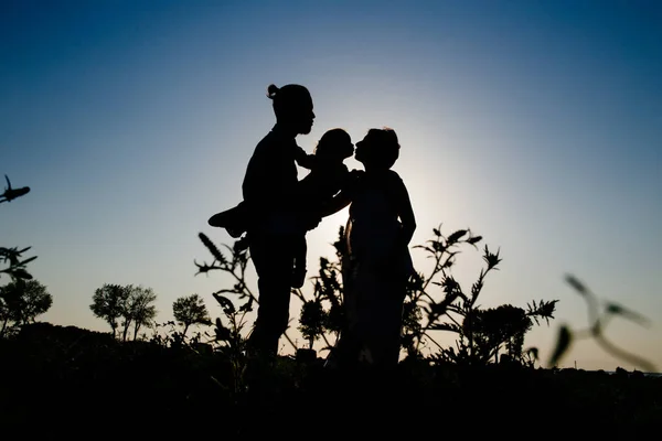 Silhueta de uma família feliz com uma criança — Fotografia de Stock