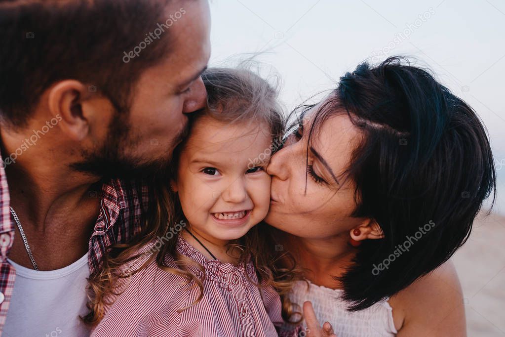 mother and father kissing  daughter