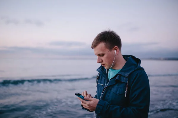 man in earphones holding smart phone.