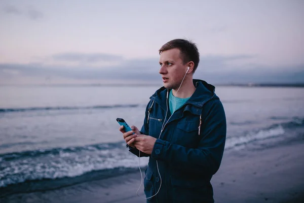 man in earphones holding smart phone